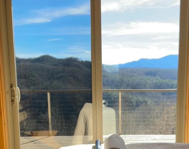 Side-by-side sliding glass door: the tinted pane shows blue sky and mountains, the untinted pane is blown out with glare