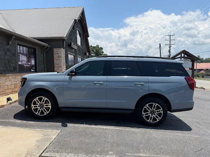 Grey SUV with tinted windows parked in front of a stone and wood building