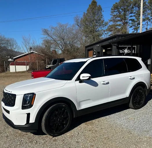 White Kia Telluride SUV with full tint package parked at the shop
